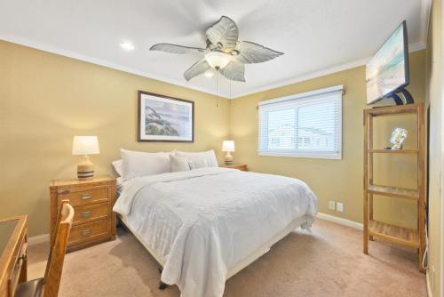 Un dormitorio con una cama blanca y un ventilador de techo. en Bay Breeze, en Lido Isle