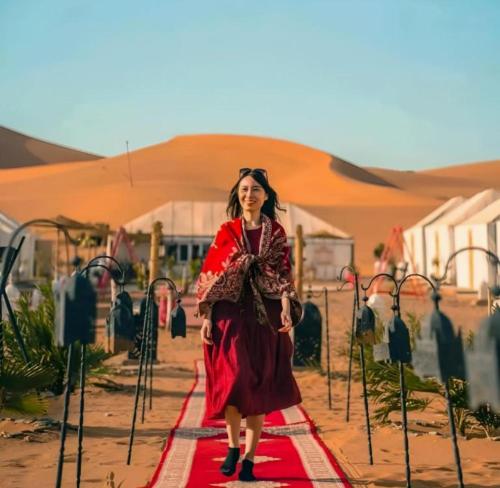 a woman in a red dress standing on a red carpet at Merzouga Top Camping in Merzouga