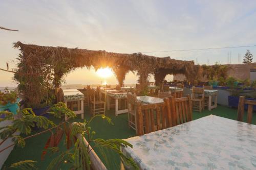 a restaurant with tables and chairs with the sunset in the background at Blue Rina Hostel in Agadir