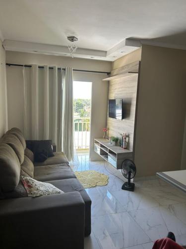 a living room with a couch and a large window at Ape completo! Wi-Fi, ar condicionado, bem localizado in Araçatuba