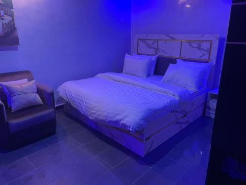 a bedroom with a bed and a chair with purple lights at DEVHAK Hotel and Suites in Warri