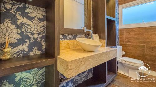 ein Badezimmer mit Waschbecken und Toilette in der Unterkunft Casa com piscina 3 suítes a 15 min Centro Gramado in Gramado