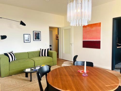 a living room with a green couch and a wooden table at Atelier Noé NOIR - Kunstvoll Wohnen - Wunderbares Frühstück möglich - Ruhig und nah am Zentrum - in Chemnitz