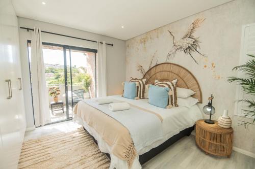 a bedroom with a large bed with a painting on the wall at Lovemore Retreat - Port Elizabeth in Gqeberha
