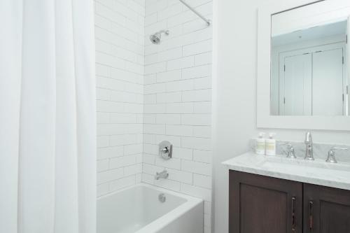 a white bathroom with a tub and a sink at The Luzianne in New Orleans