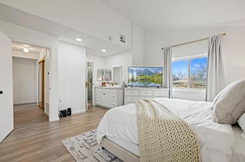a white bedroom with a large bed and a television at Modern Private 3B-2BA Home and Spacious Yard in Lancaster