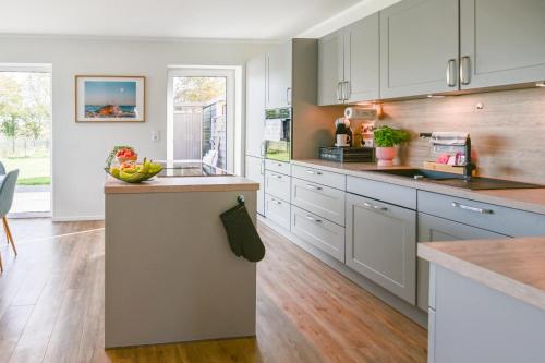 una cocina con armarios blancos y un bol de fruta en una barra en Feldbrise-Fehmarn, en Fehmarn