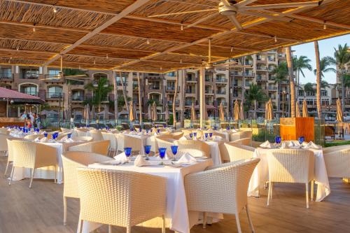 a restaurant with white tables and chairs and a building at Villa Del Palmar Flamingos Beach Resort & Spa in Nuevo Vallarta