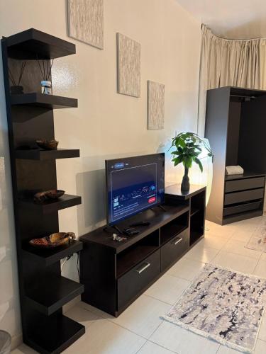 a living room with a tv and a black entertainment center at Studio in Ajman Corniche in Ajman