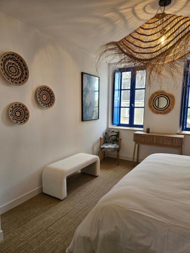 a bedroom with a bed and a bench and windows at Les Volets Bleus house and spa in Jublains