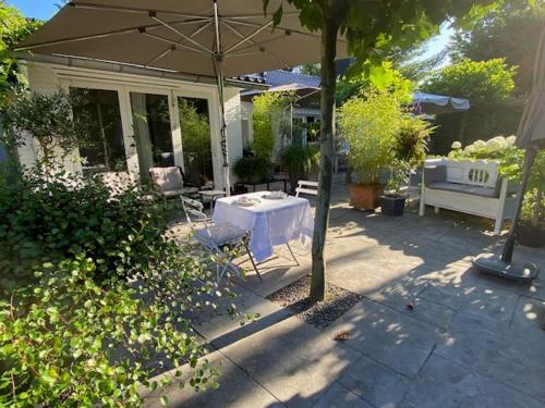 eine Terrasse mit Sonnenschirm und Tisch und Stühlen in der Unterkunft Bed and Breakfast Valckenbosch in Zeist
