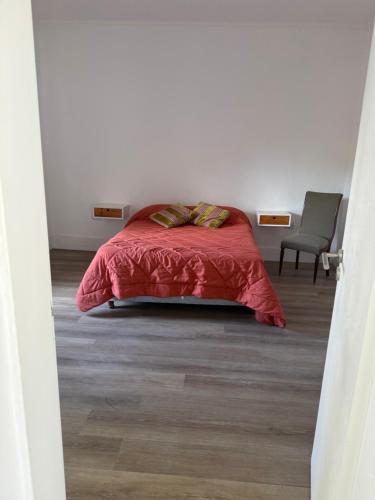 a bedroom with a bed with a red comforter and a chair at Saladillo House in Saladillo
