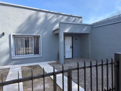 a white house with a fence and a door at Saladillo House in Saladillo