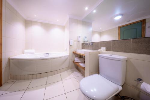 a white bathroom with a toilet and a sink at Almasur Punta Arenas in Punta Arenas