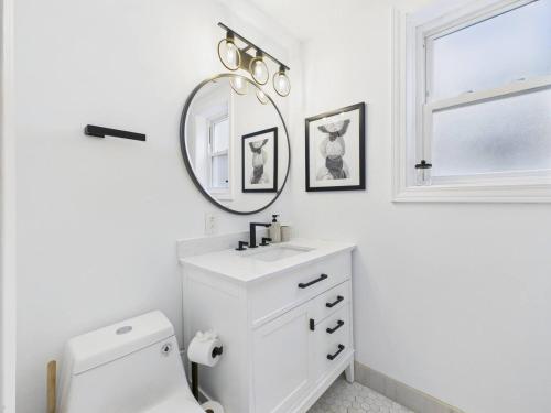 ein weißes Badezimmer mit Waschbecken und Spiegel in der Unterkunft Game Day Stay Steps to Wrigley Garage in Chicago