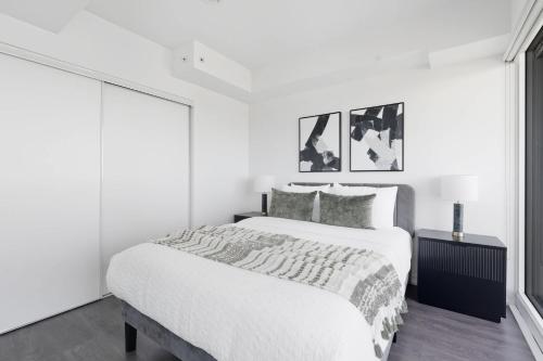 a white bedroom with a large bed and a window at Bright 2BR Downtown Toronto Condo in Toronto