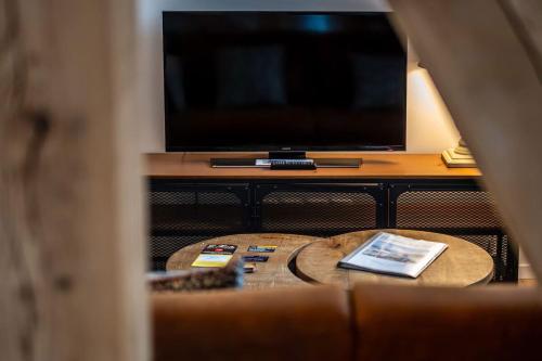 een woonkamer met een tafel en een televisie bij Une petite vue sur le Paradis in Orbey