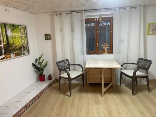 ein Esszimmer mit 2 Stühlen, einem Tisch und einem Fenster in der Unterkunft LE COCON - Calme et Ressourcement in Rouffach