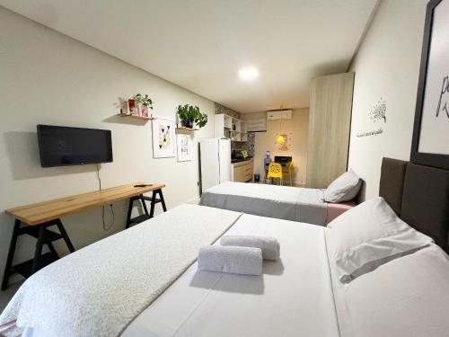 ein Zimmer mit zwei Betten und einem Schreibtisch und einem Fernseher in der Unterkunft 700m da Praia de Atalaia com ar e piscina in Santa Maria