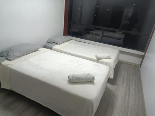 two beds in a room with a large window at 402 El Jardín Apartamento La Carolina Quito in Quito