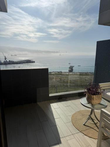 a balcony with a table and a view of the ocean at HOM Depto 4PAX con Parking En cerro Baron in Valparaíso