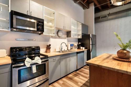 a kitchen with stainless steel appliances and wooden floors at Soaring Designer Ceiling Condo near Market Square in Knoxville