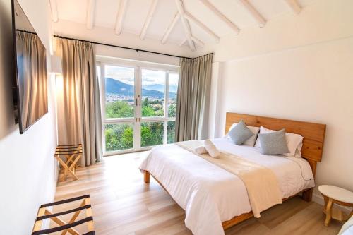 ein Schlafzimmer mit einem Bett und einem großen Fenster in der Unterkunft Familiares casas de campo con vista increíble in Villa de Leyva