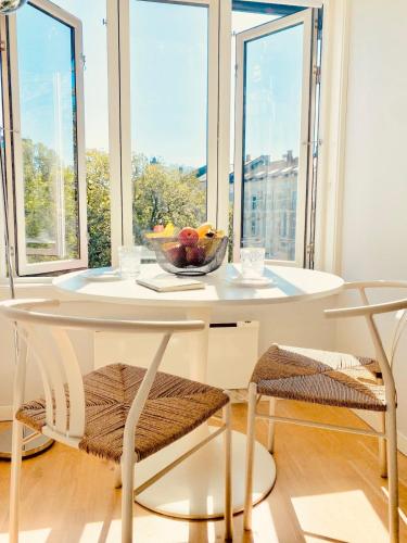 a white table with a bowl of fruit and two chairs at Refined and Ultra-Central Apartment Studio in Oslo