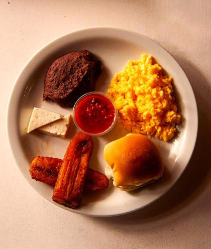 a plate of breakfast food with eggs sausage and meat at Hotel Tortuga Village in La Herradura