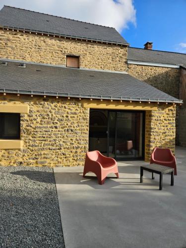 two chairs and a bench in front of a building at Les Volets Bleus house and spa in Jublains