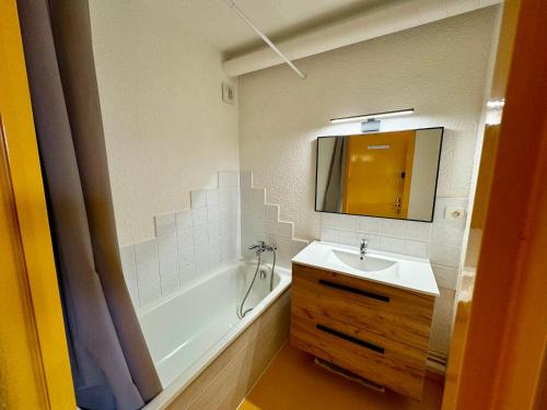Un baño con lavabo, bañera y espejo. en Le Chalet de Bisanne, en Les Saisies