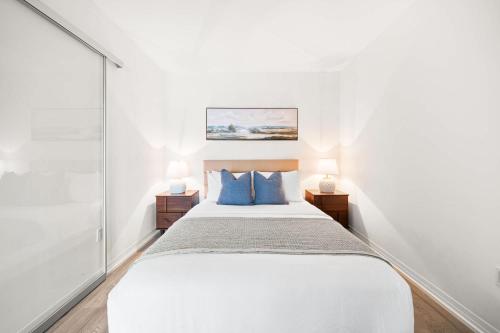 a white bedroom with a bed with blue pillows at City Living Downtown Retreat Perfect Getaway in Toronto