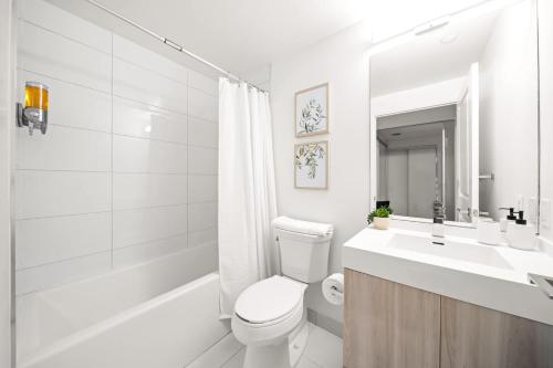 a white bathroom with a toilet and a sink at City Living Downtown Retreat Perfect Getaway in Toronto