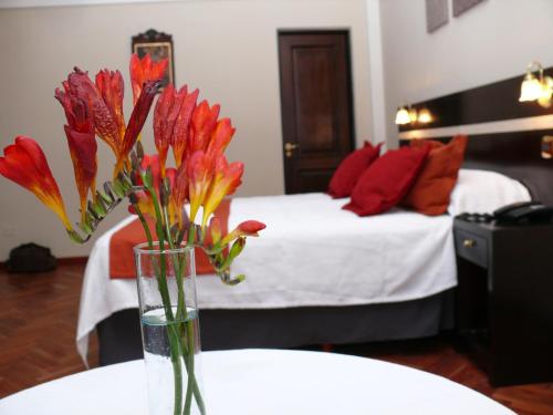 a vase of flowers sitting on a table in a bedroom at Gregorio I Hotel Boutique in San Salvador de Jujuy