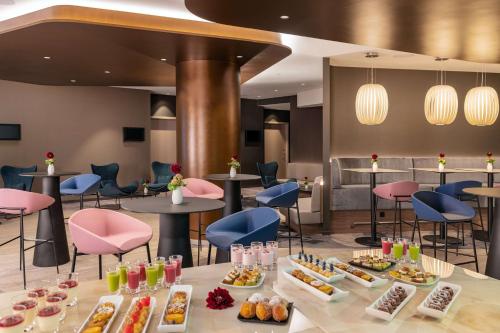 ミュンヘンにあるNH Collection München Bavariaのテーブルと椅子があり、食べ物が置かれているレストラン