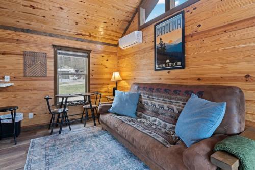 un soggiorno con un divano e un tavolo di All Tuckered Out - Riverfront Cabin, Fish, Hike & 5 Minutes to Sylva! a Sylva