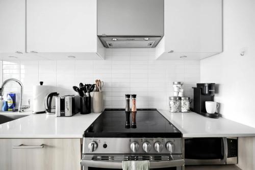 a kitchen with a stainless steel stove and white cabinets at Luxe Downtown Studio Near Eaton Centre & Transit in Toronto