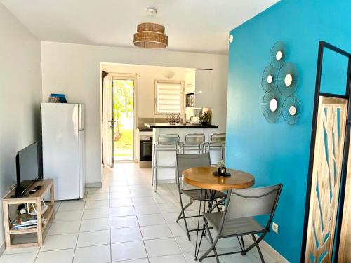 a kitchen with a table and chairs and a blue wall at Studio - Résidence avec piscine in Sainte-Anne
