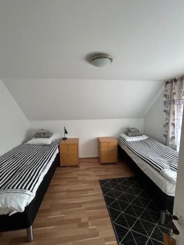 two twin beds in a room with wooden floors at Motel Villa Søndervang 3 personers værelse in Harndrup