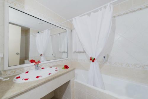 een badkamer met een wastafel, een bad en een spiegel bij Hotel El Habib Monastir in Monastir