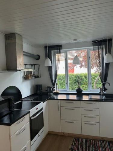 a kitchen with white cabinets and a large window at Motel Villa Søndervang 3 personers værelse in Harndrup