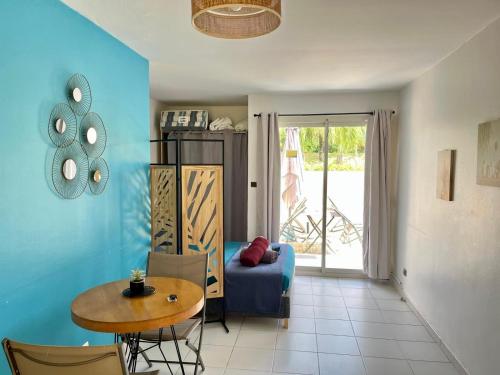 a living room with a table and a blue wall at Studio - Résidence avec piscine in Sainte-Anne