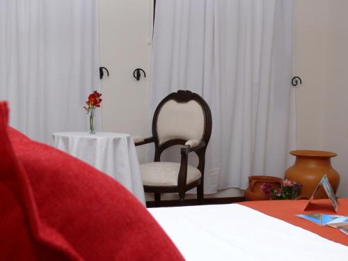 a bedroom with a chair and a table with a vase of flowers at Gregorio I Hotel Boutique in San Salvador de Jujuy