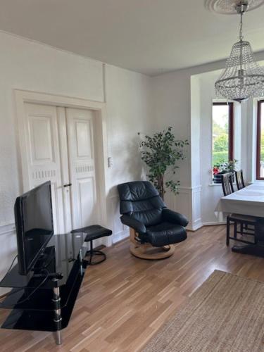 a living room with a tv and a chair at Motel Villa Søndervang 3 personers værelse in Harndrup