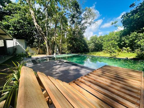 a swimming pool with a wooden bench next to it at Monkey Banana Villa in Galle