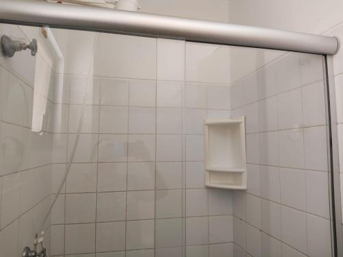 a white tiled shower with a soap dispenser in a bathroom at Flat Pé na Areia em Guarajuba Summer House, Bahia in Monte Gordo