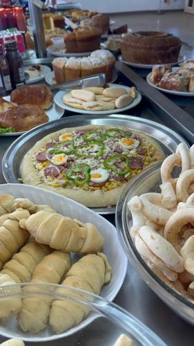 ein Buffet mit Kuchen und Pizza auf Tellern in der Unterkunft Hotel Via Montes in Montes Claros