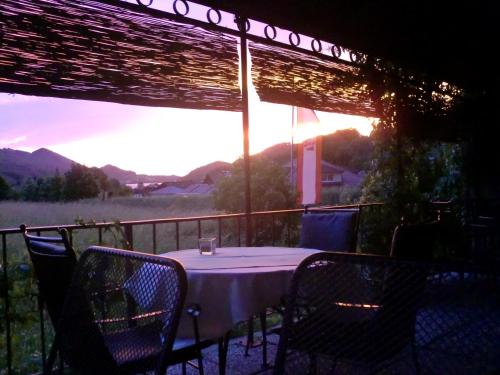einen Tisch und Stühle auf einem Balkon mit Blick auf den Sonnenuntergang in der Unterkunft Steakhouse Fieg in Fuschl am See