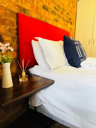 1 cama con cabecero rojo y mesa de madera en Luu's Balcony, en Johannesburgo