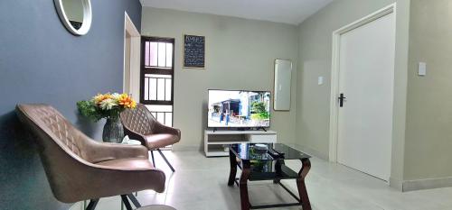 a living room with two chairs and a tv at Closer to CBD by UrbanCove in Nelspruit